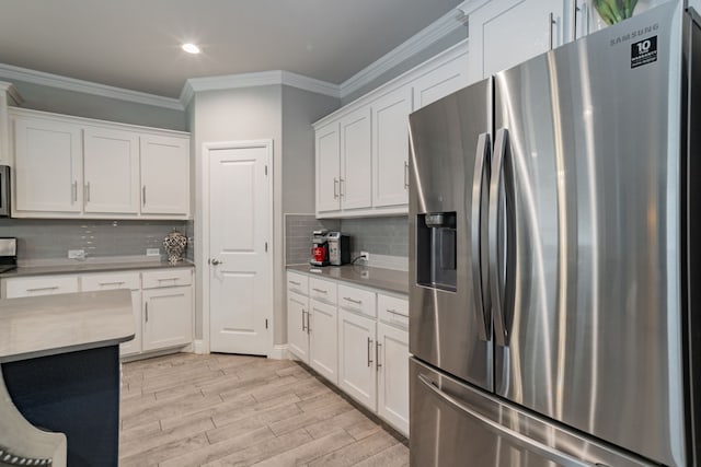 kitchen featuring tasteful backsplash, ornamental molding, stainless steel appliances, white cabinets, and light hardwood / wood-style floors