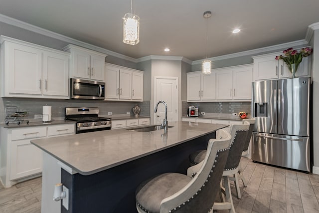 kitchen featuring appliances with stainless steel finishes, light wood-type flooring, decorative light fixtures, and sink