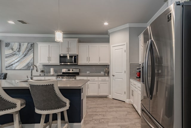 kitchen with backsplash, white cabinetry, hanging light fixtures, and stainless steel appliances