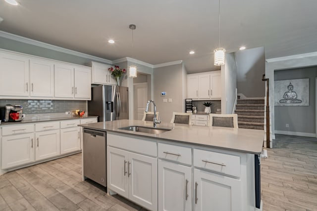 kitchen with pendant lighting, stainless steel appliances, white cabinetry, and sink