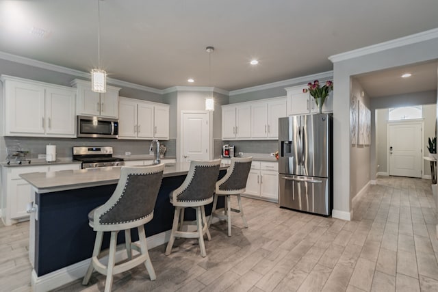 kitchen featuring pendant lighting, light wood-type flooring, an island with sink, white cabinetry, and stainless steel appliances