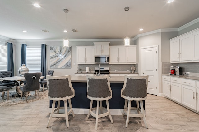 kitchen featuring white cabinetry, hanging light fixtures, and appliances with stainless steel finishes