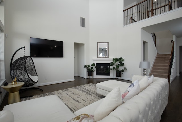 living room with dark hardwood / wood-style flooring and a towering ceiling