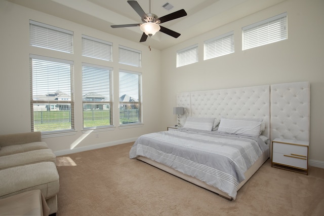 bedroom with ceiling fan, light colored carpet, and multiple windows