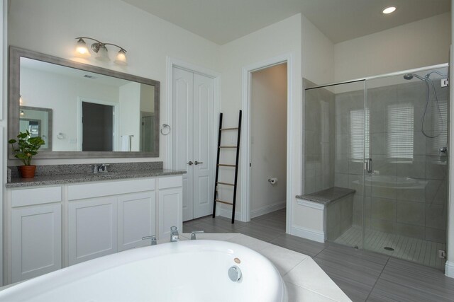 bathroom featuring tile patterned flooring, vanity, and plus walk in shower