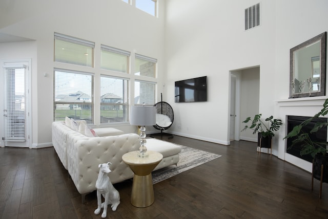 living room featuring a towering ceiling and dark wood-type flooring