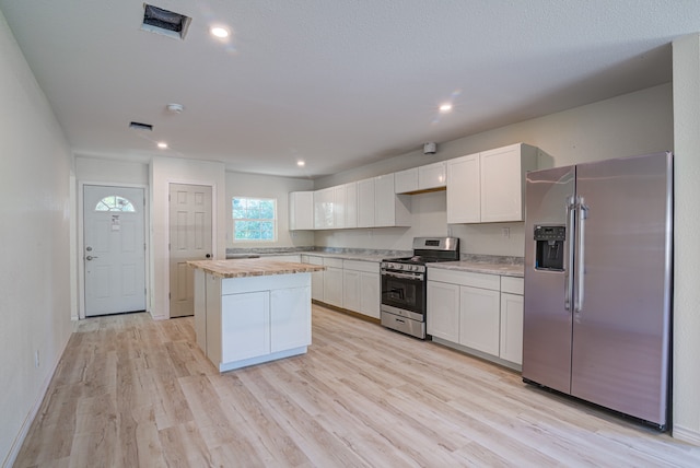 kitchen with white cabinetry, light hardwood / wood-style flooring, a center island, and stainless steel appliances