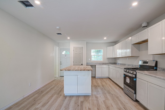 kitchen with stainless steel gas stove, white cabinets, light hardwood / wood-style flooring, and a kitchen island