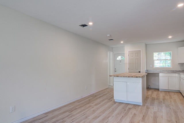 kitchen with white cabinetry, a kitchen island, and light hardwood / wood-style floors