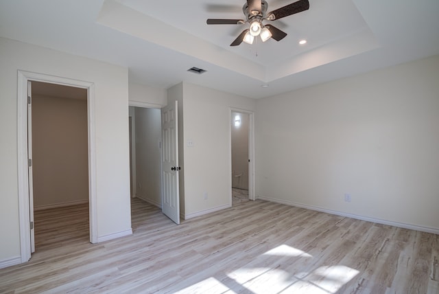 unfurnished bedroom with a tray ceiling, light hardwood / wood-style flooring, and ceiling fan