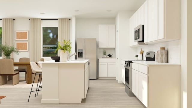 kitchen featuring a center island, backsplash, white cabinets, appliances with stainless steel finishes, and a breakfast bar area