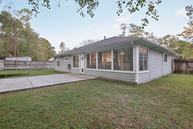 back of house featuring a lawn, a patio, and a trampoline