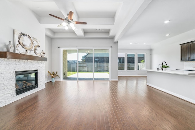 unfurnished living room featuring ceiling fan, a fireplace, wood-type flooring, and sink