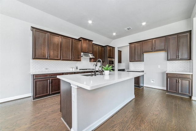 kitchen with stainless steel appliances, backsplash, a center island with sink, and dark hardwood / wood-style floors