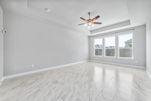 empty room featuring a raised ceiling and ceiling fan