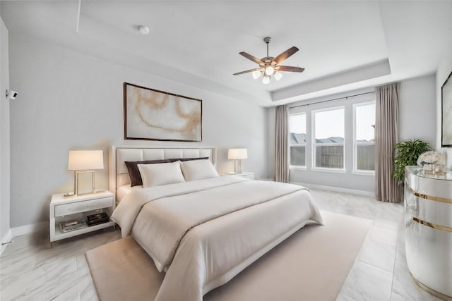 bedroom with ceiling fan and a tray ceiling