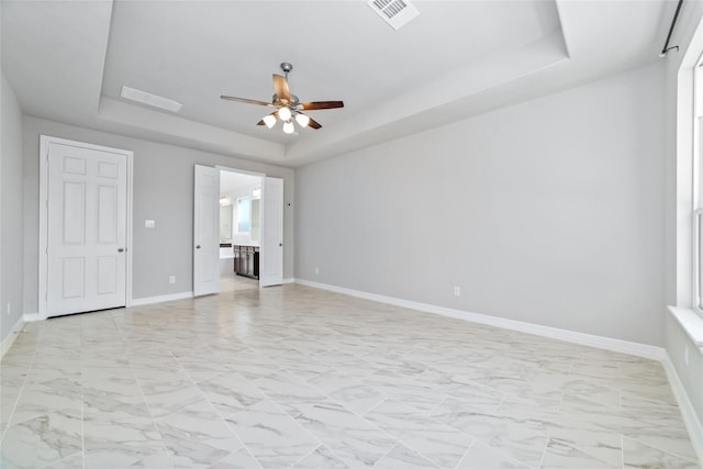 spare room featuring a raised ceiling and ceiling fan