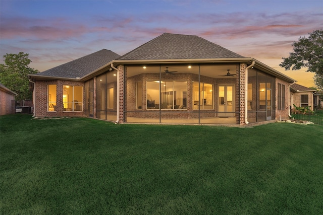 back house at dusk with a yard, a patio, and ceiling fan