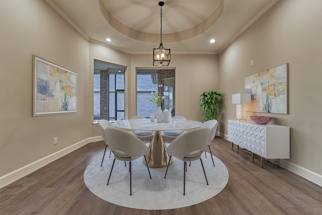 dining space featuring a chandelier, wood-type flooring, a tray ceiling, and crown molding