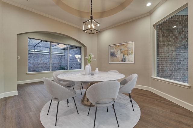 dining area featuring a notable chandelier, dark hardwood / wood-style floors, ornamental molding, and a tray ceiling