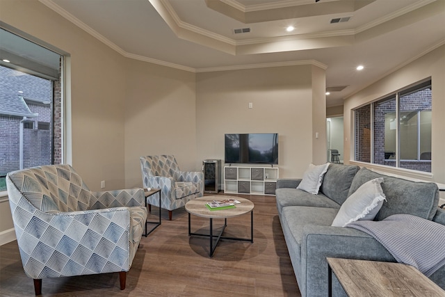 living room featuring a raised ceiling, crown molding, and hardwood / wood-style floors