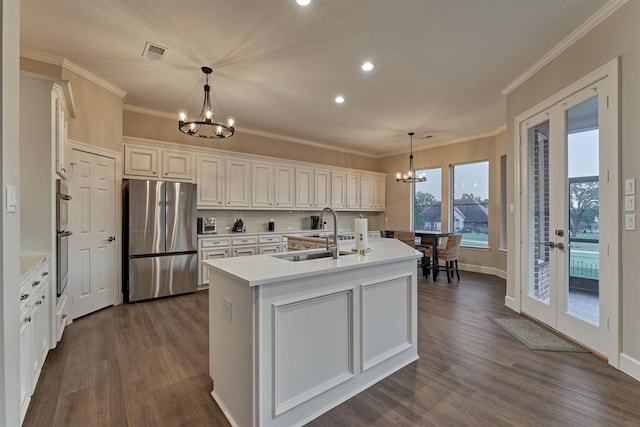 kitchen with an island with sink, stainless steel appliances, a notable chandelier, and sink