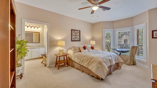 bedroom with connected bathroom, light colored carpet, and ceiling fan