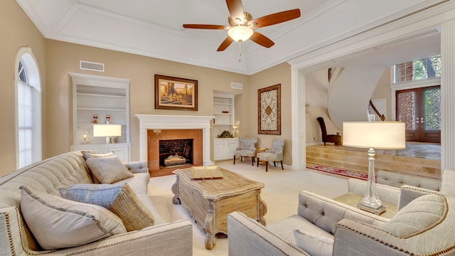 carpeted living room with ornamental molding, built in features, ceiling fan, and french doors