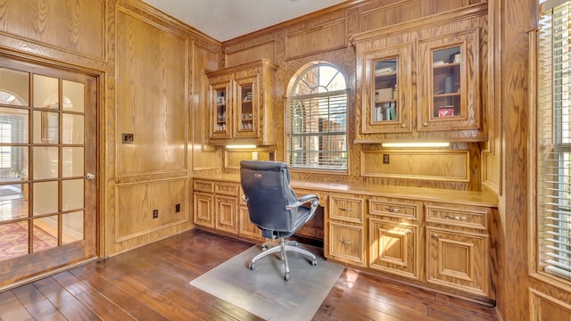 home office featuring dark wood-type flooring, built in desk, and wood walls