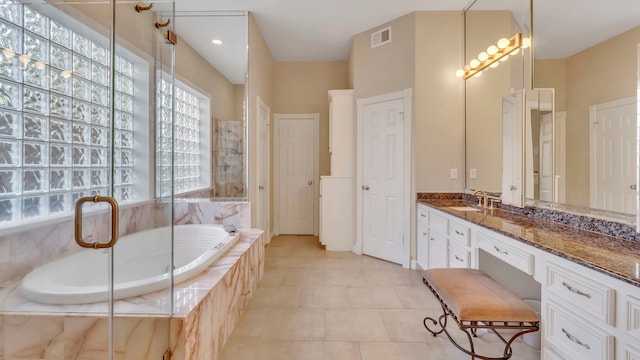 bathroom featuring tile patterned flooring, vanity, and a relaxing tiled tub