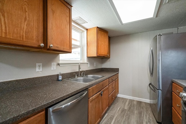 kitchen with hardwood / wood-style floors, sink, stainless steel appliances, and a textured ceiling