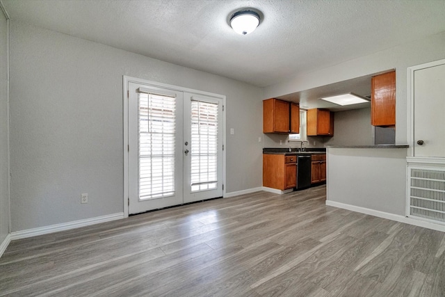 kitchen featuring dishwasher, french doors, sink, light hardwood / wood-style floors, and a textured ceiling