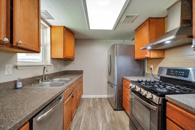 kitchen featuring stainless steel appliances, light hardwood / wood-style flooring, wall chimney exhaust hood, and sink