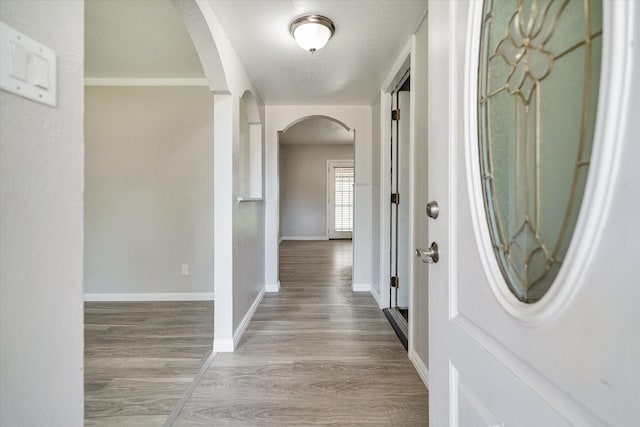 corridor with a textured ceiling and light wood-type flooring