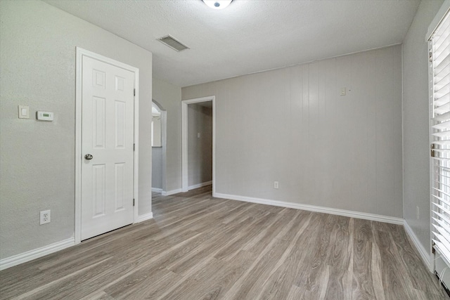 unfurnished room featuring a textured ceiling and light hardwood / wood-style flooring