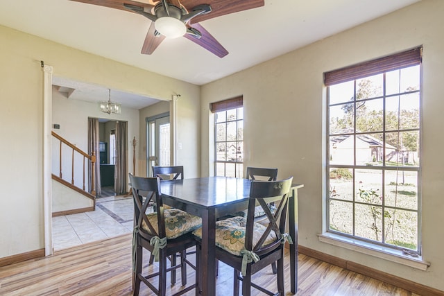 dining space featuring ceiling fan with notable chandelier, light hardwood / wood-style flooring, and a healthy amount of sunlight