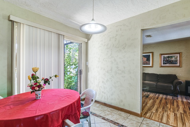 dining area with a textured ceiling and light hardwood / wood-style flooring