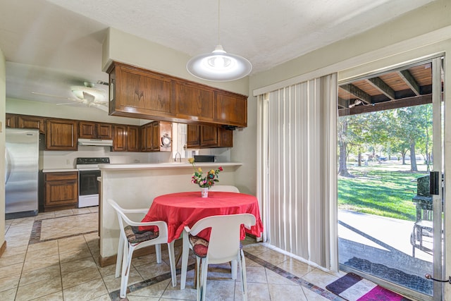 kitchen featuring kitchen peninsula, light tile patterned floors, pendant lighting, white electric range, and stainless steel refrigerator