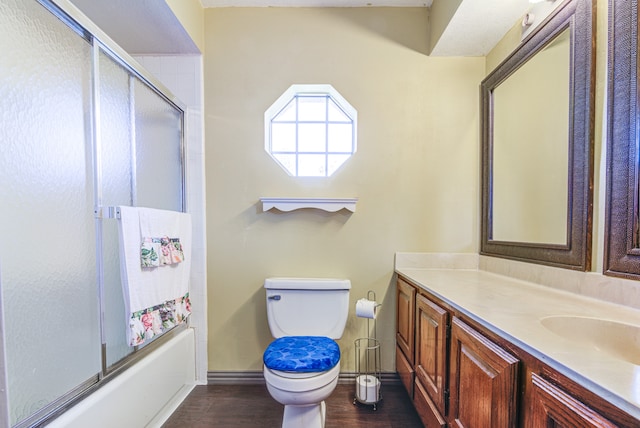 full bathroom with shower / bath combination with glass door, hardwood / wood-style floors, vanity, and toilet