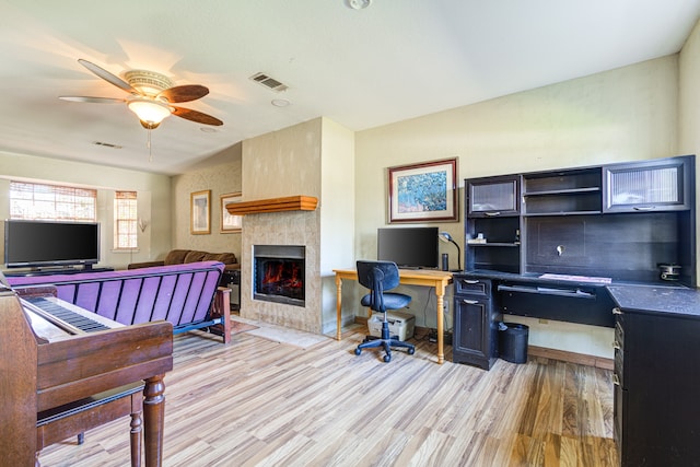 office area with ceiling fan, light hardwood / wood-style floors, and a fireplace