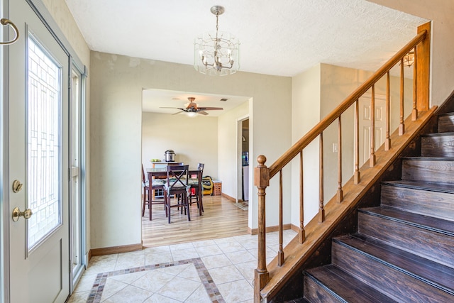 entrance foyer featuring a textured ceiling, plenty of natural light, light hardwood / wood-style floors, and ceiling fan with notable chandelier