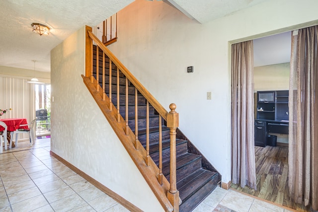 staircase featuring hardwood / wood-style floors and a textured ceiling