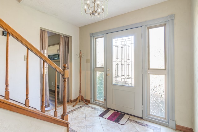 tiled entrance foyer featuring a textured ceiling and an inviting chandelier