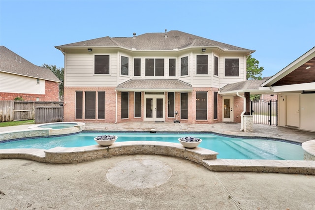 rear view of property with a swimming pool with hot tub and french doors