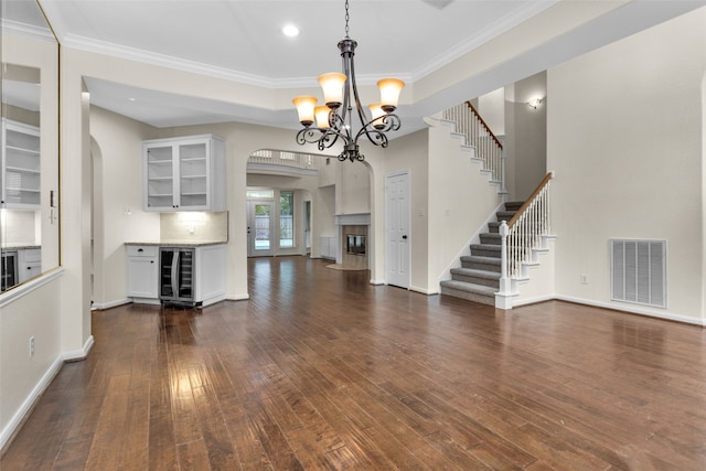 unfurnished living room featuring a chandelier, dark hardwood / wood-style flooring, wine cooler, and crown molding