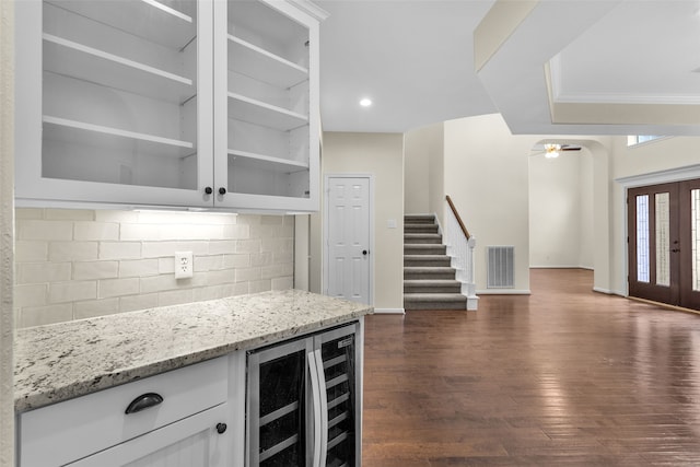 bar featuring dark hardwood / wood-style flooring, tasteful backsplash, light stone counters, beverage cooler, and white cabinets