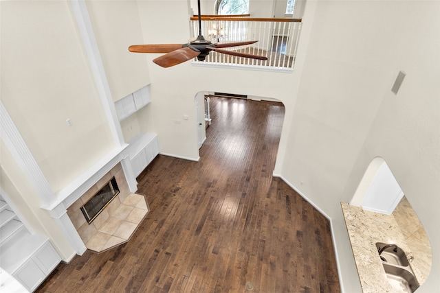 stairway featuring a fireplace, wood-type flooring, a towering ceiling, and ceiling fan