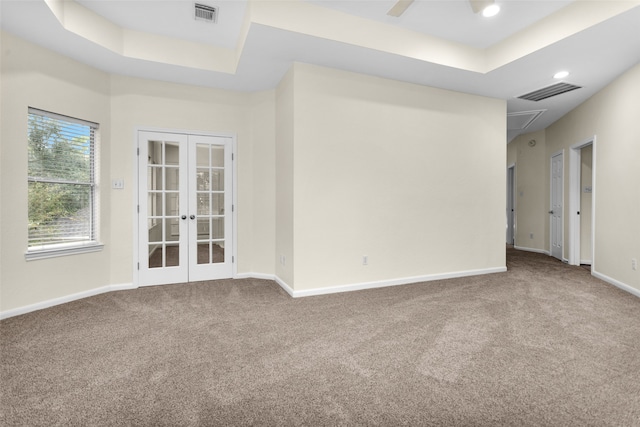 empty room with ceiling fan, carpet floors, a tray ceiling, and french doors