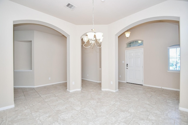 unfurnished room featuring a chandelier