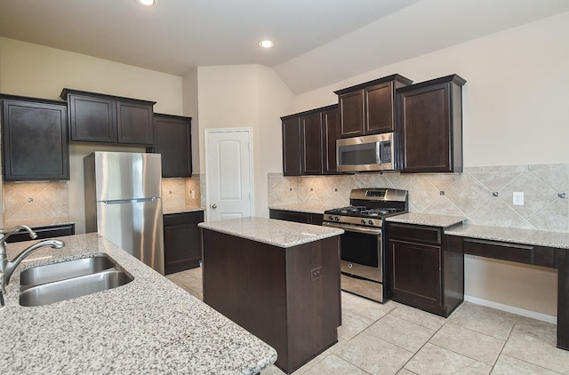 kitchen featuring backsplash, a kitchen island, sink, light stone countertops, and stainless steel appliances